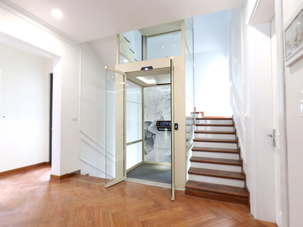 Cibes V90 home lift installed beside a staircase inside a modern villa, featuring glass shaft and marble-patterned back panel.