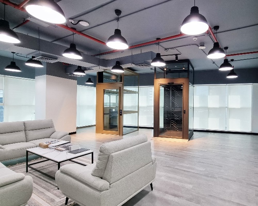 Cibes Abu Dhabi showroom interior with two demo home lifts in glass shafts and lounge seating.