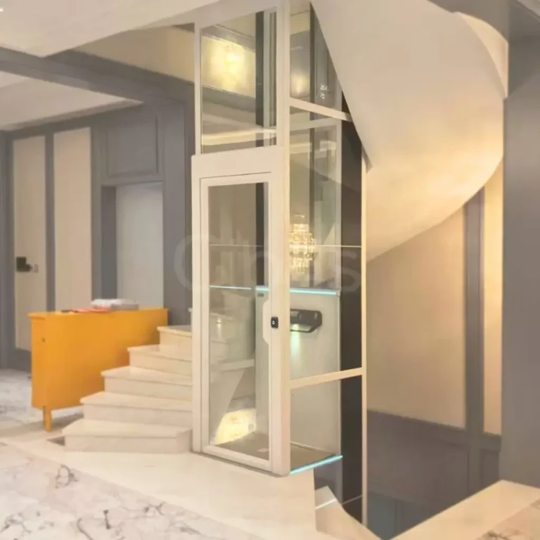 Compact glass home lift in a stairwell corner, space-saving installation with a panoramic shaft inside a residential interior.
