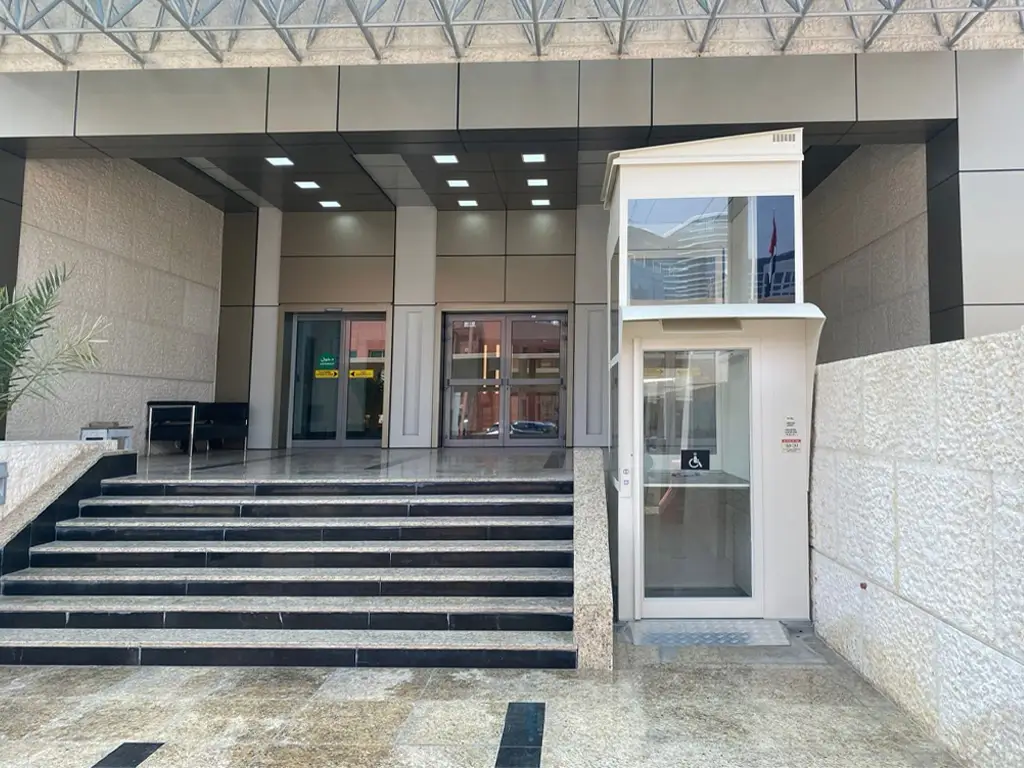 Cibes Voyager platform lift installed at the entrance of Abu Dhabi Courthouse, providing wheelchair accessibility beside the main stairs.