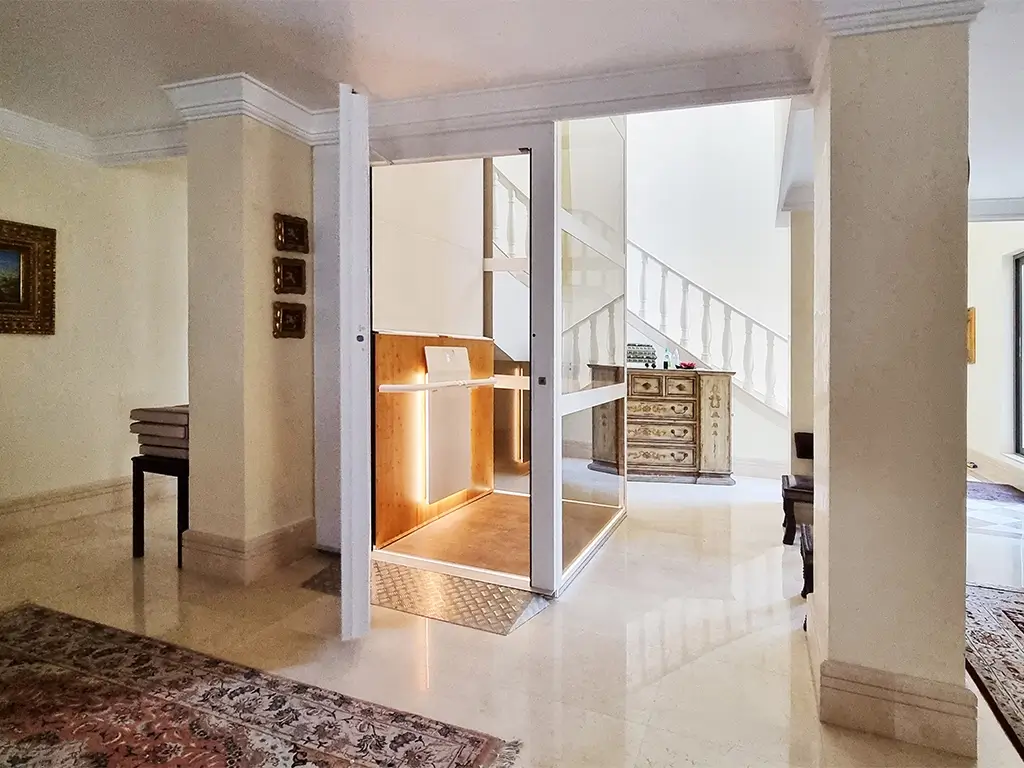 Cibes Air platform lift installed in a luxurious UAE penthouse, featuring glass panels and warm wood interior lighting for an elegant home elevator experience.