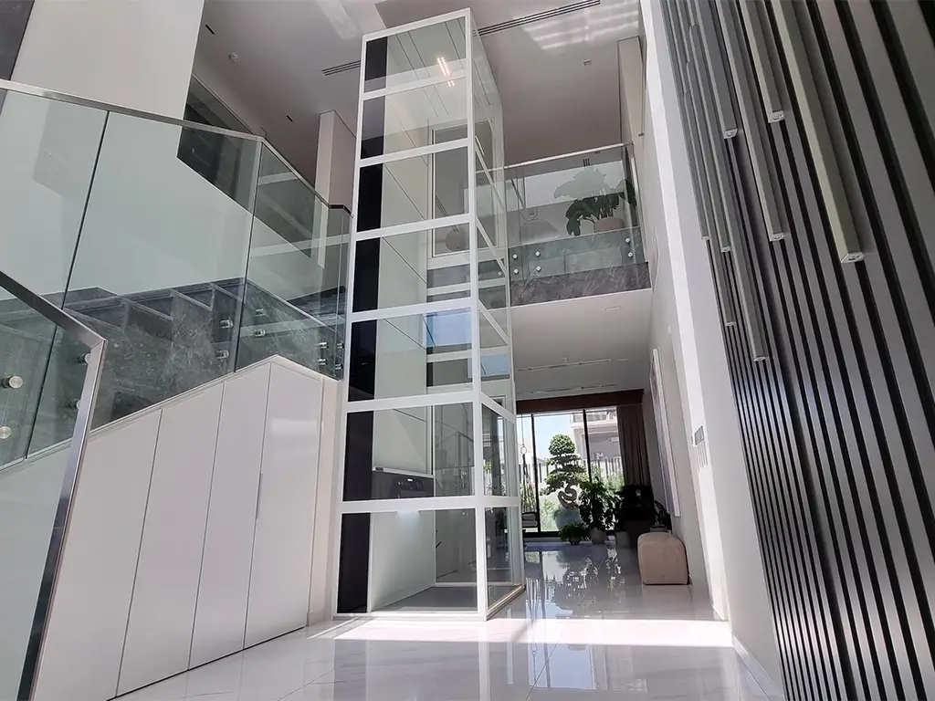 Modular home lift with glass shaft installed in a UAE villa, showing a no pit and no machine room screw-driven lift design.