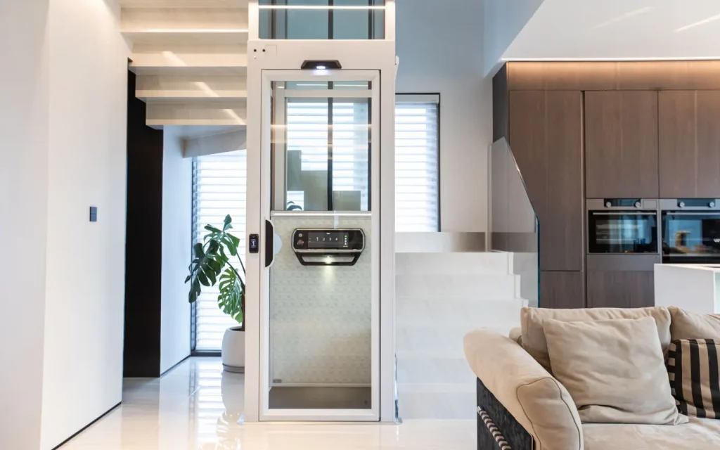 Compact home lift installed inside a modern villa living room with staircase nearby.